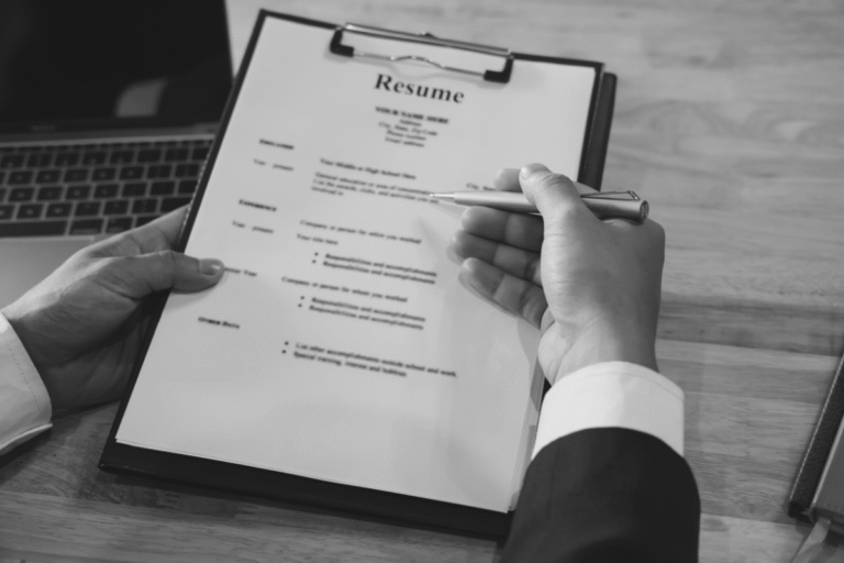 Close-up of a person reviewing a resume on a clipboard with a pen in hand