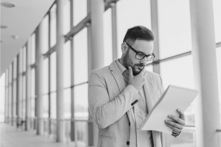 Thoughtful businessman reviewing notes in a bright office hallway